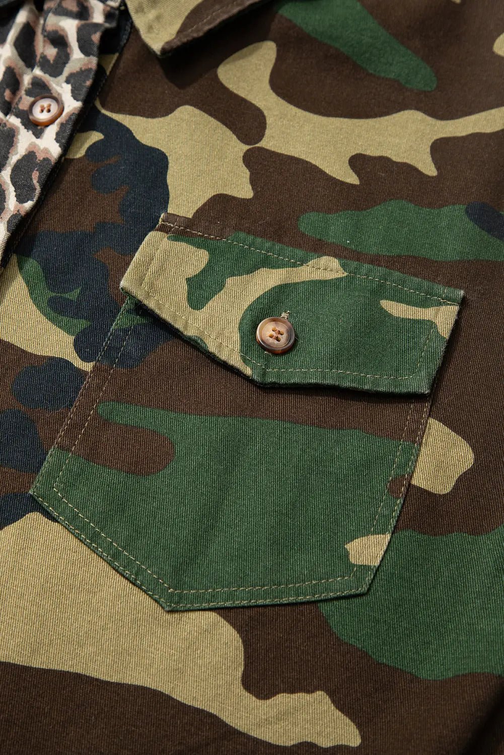 Close-up of a camouflage shirt with a button and pocket detail.
