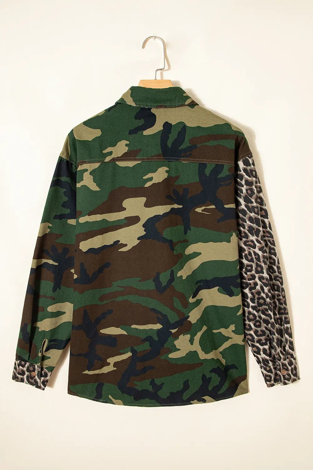 Camouflage shirt with leopard print sleeves on a hanger against a white background
