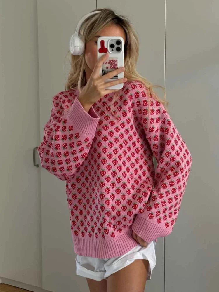 Person wearing a pink sweater with a red pattern, taking a mirror selfie.