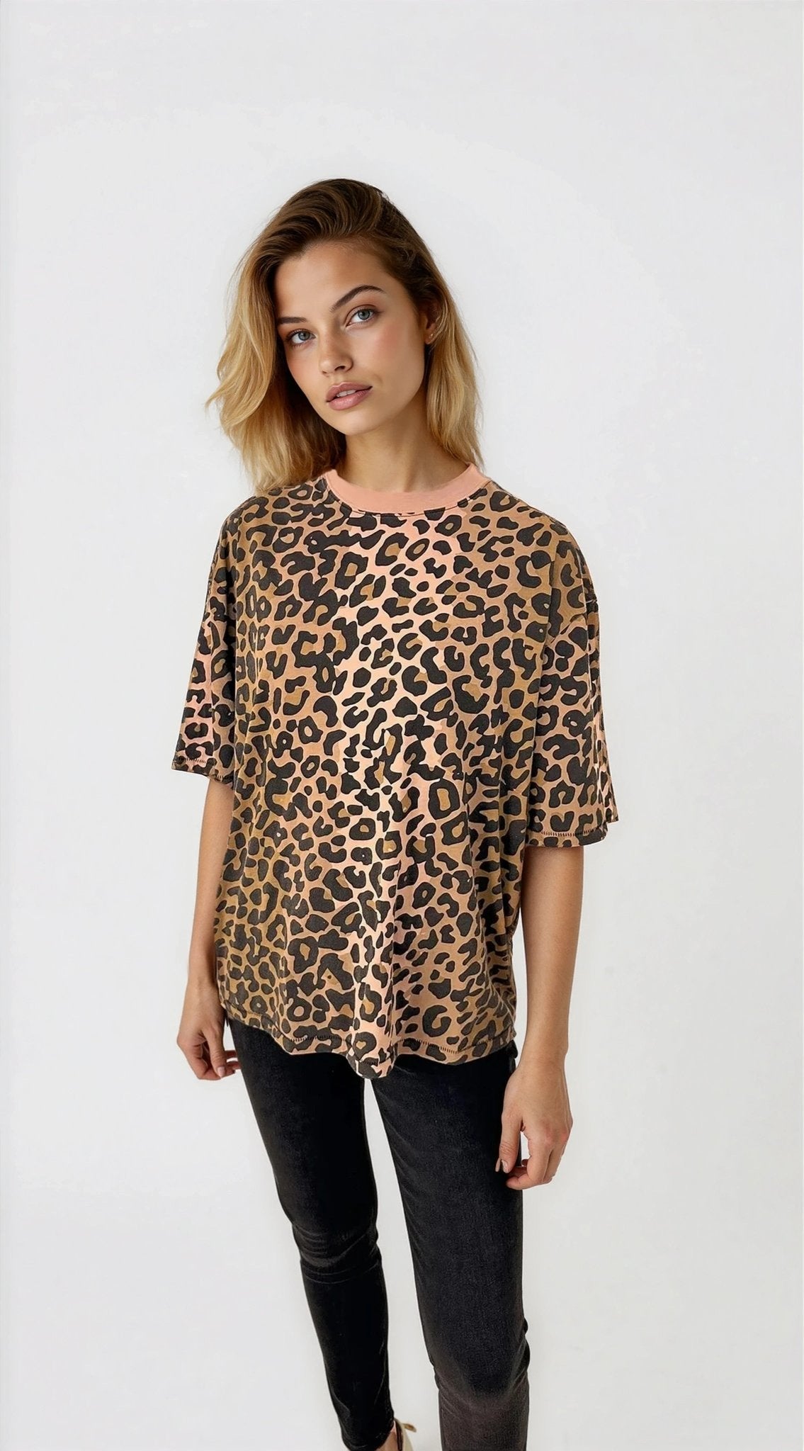 Woman wearing a leopard print top and black pants on a white background