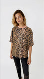 Woman wearing a leopard print top and black pants on a white background