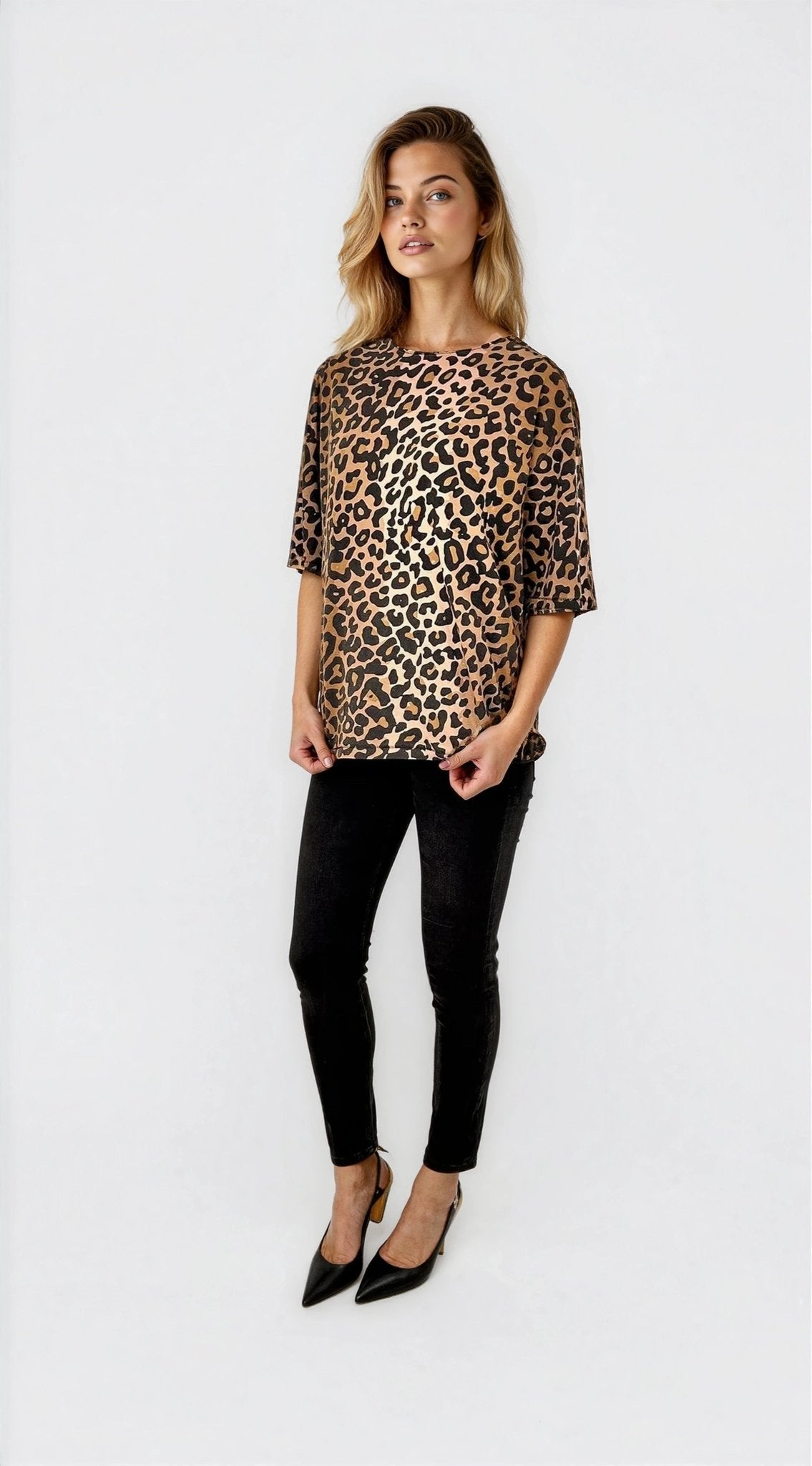 Woman wearing a leopard print top and black pants on a white background