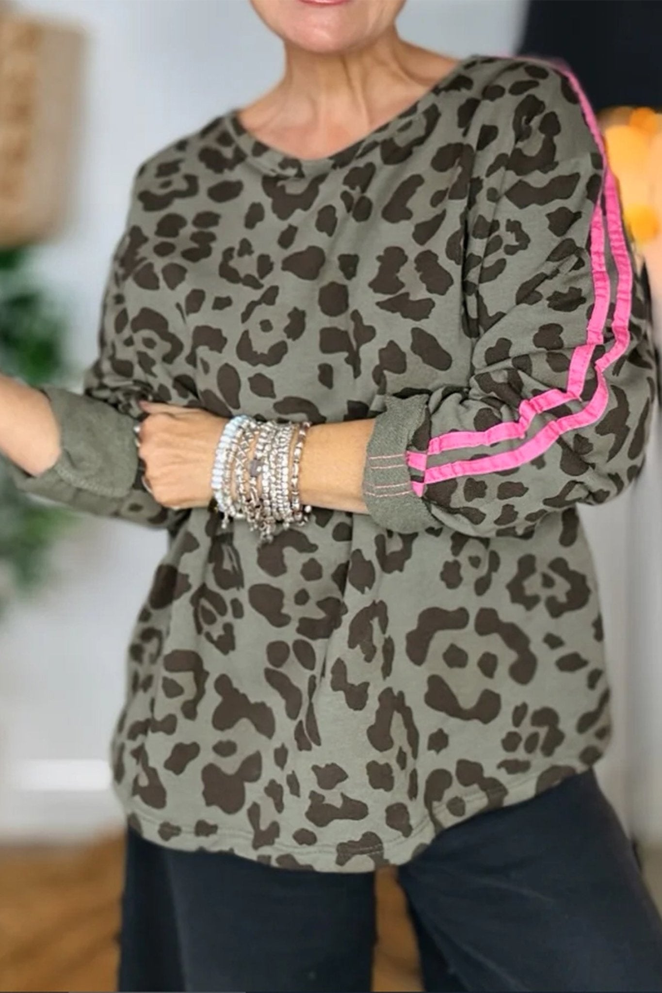 Person wearing a leopard print top with pink trim in an indoor setting