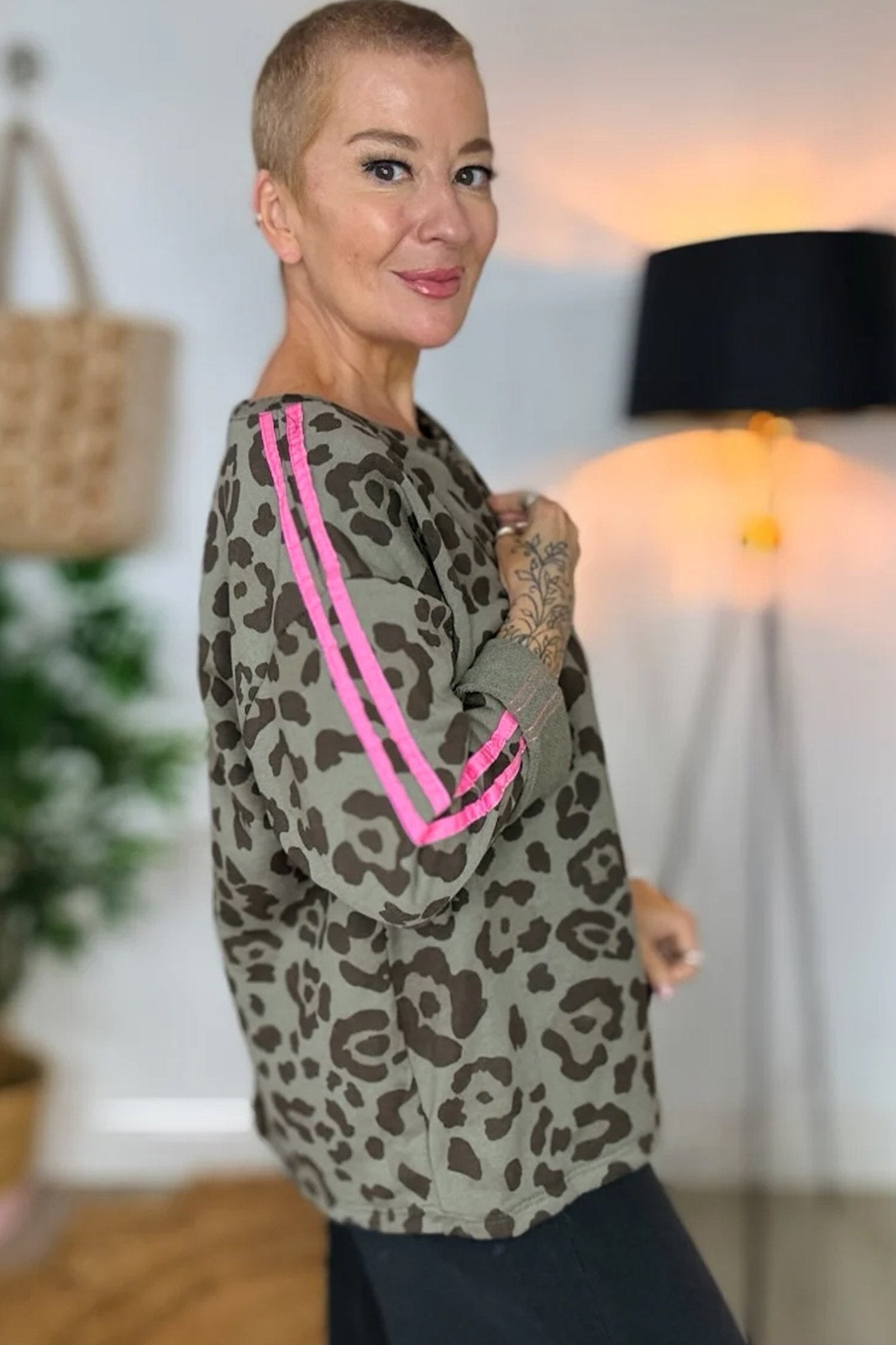 Person wearing a leopard print top with pink stripes in a home setting