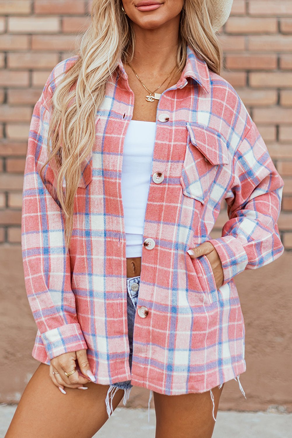 Person wearing a plaid shirt in front of a brick wall