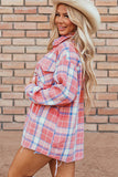 Woman wearing a plaid shirt and cowboy hat against a brick wall.