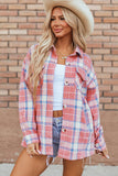 Woman wearing a plaid shirt over a white top and denim shorts, standing against a brick wall.