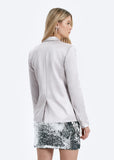 Woman wearing a light gray blazer and sequin skirt on a white background