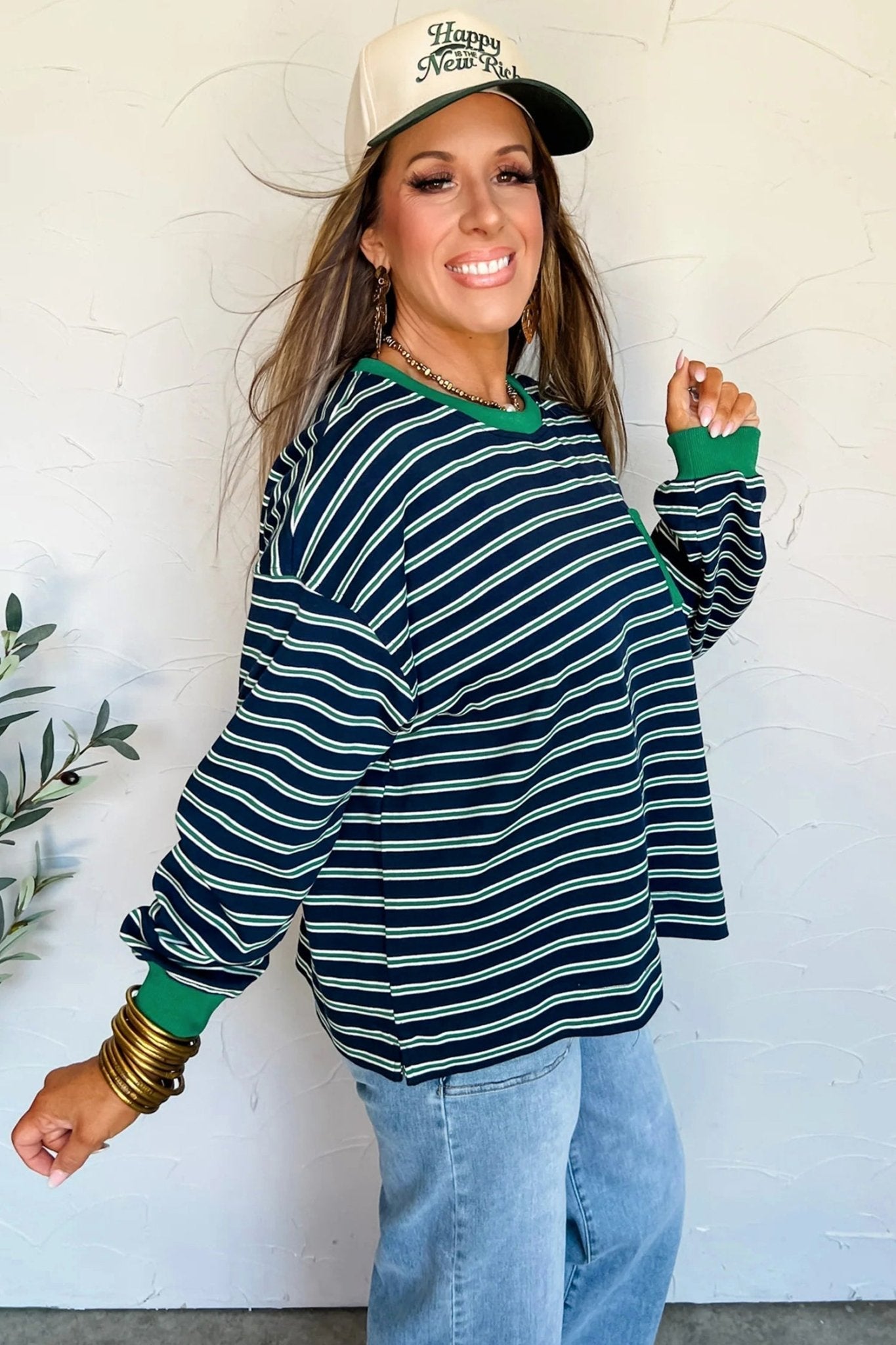 Woman wearing a striped sweater and cap against a white wall
