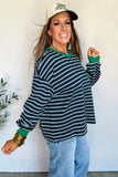 Woman wearing a striped sweater and cap against a white wall