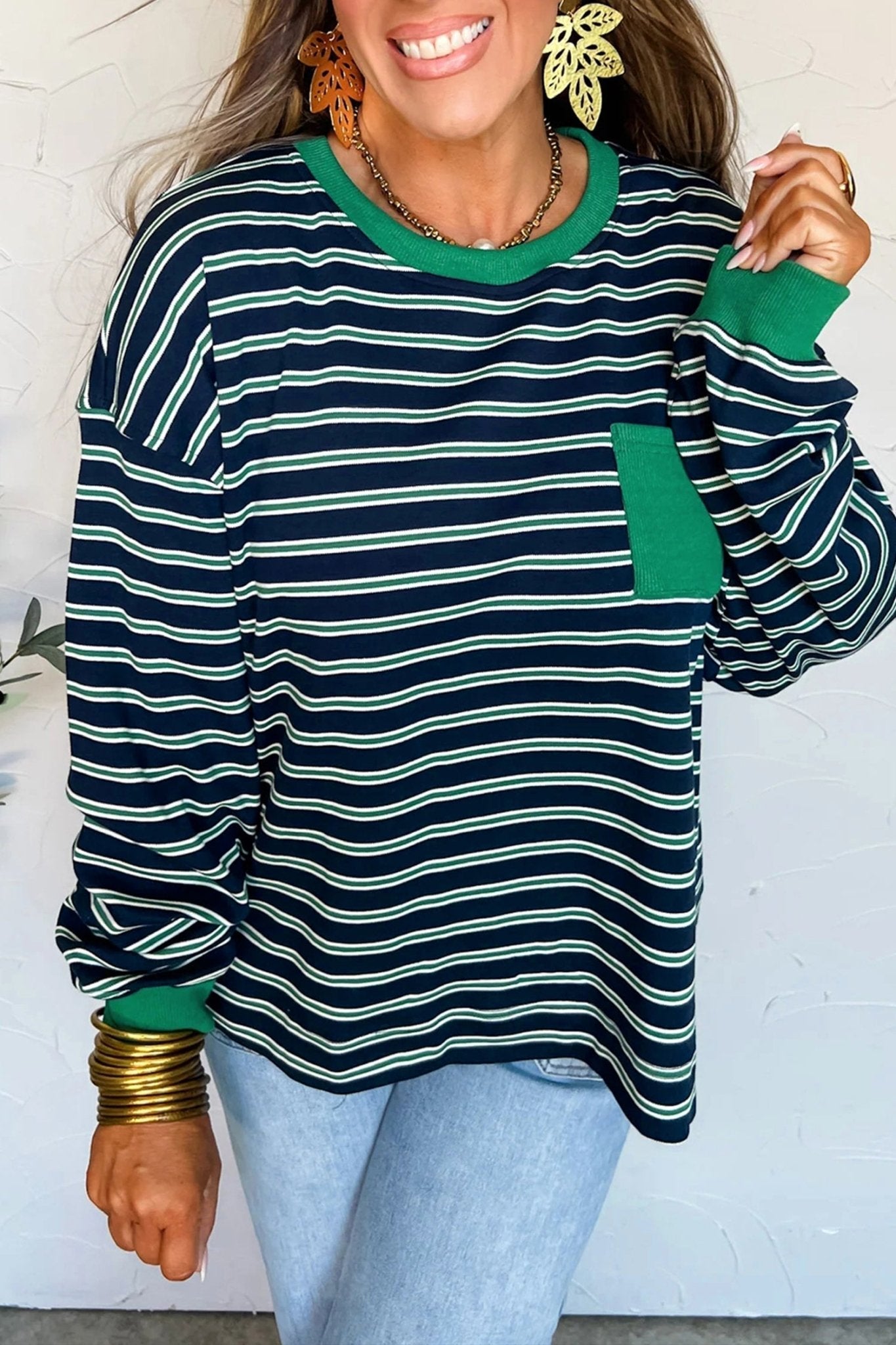 Woman wearing a green and navy striped sweater with a white background