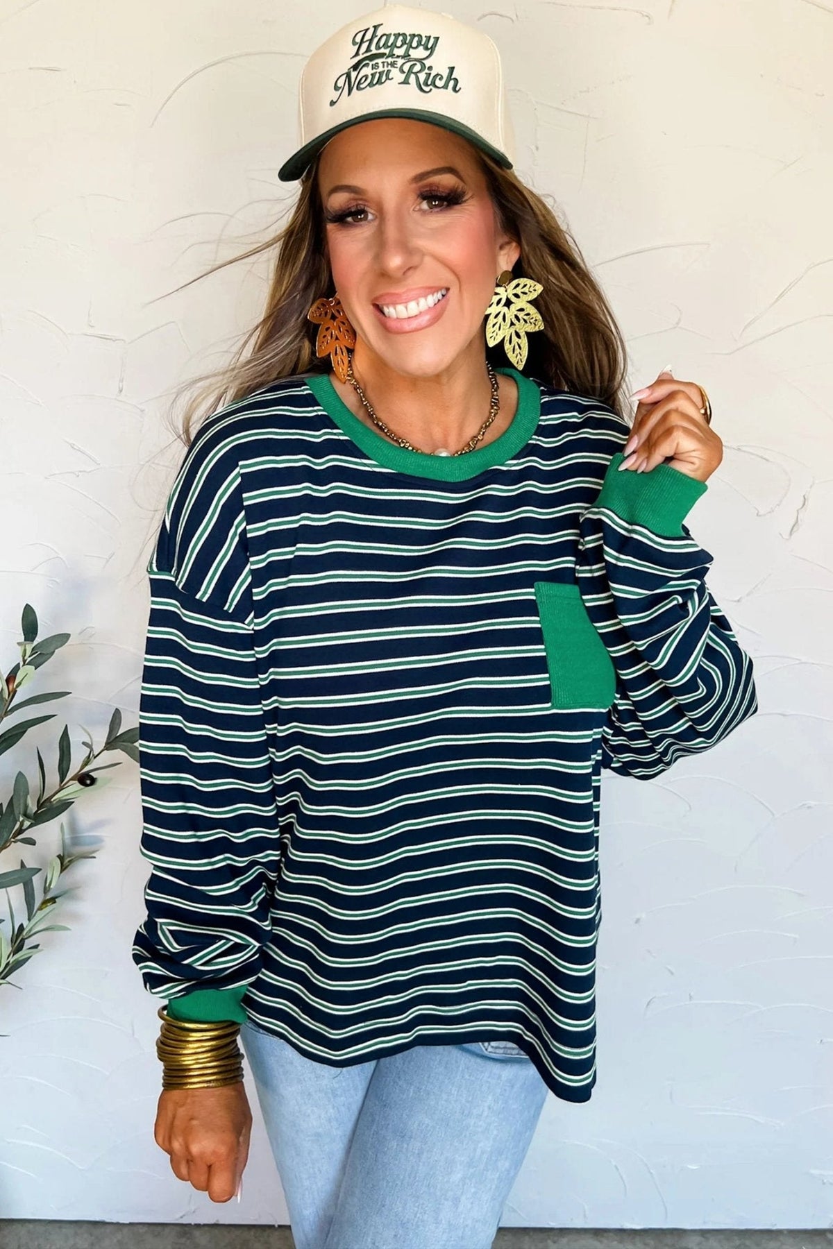 Woman wearing a striped sweater and cap with a plant in the background