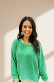 Woman wearing a green sweater with a neutral background