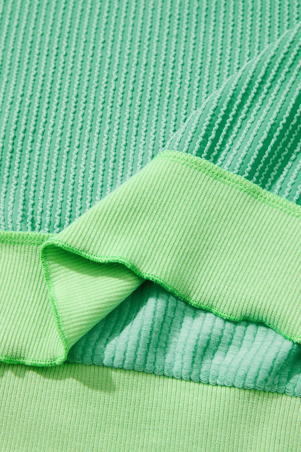 Close-up of green textured fabric with a folded edge