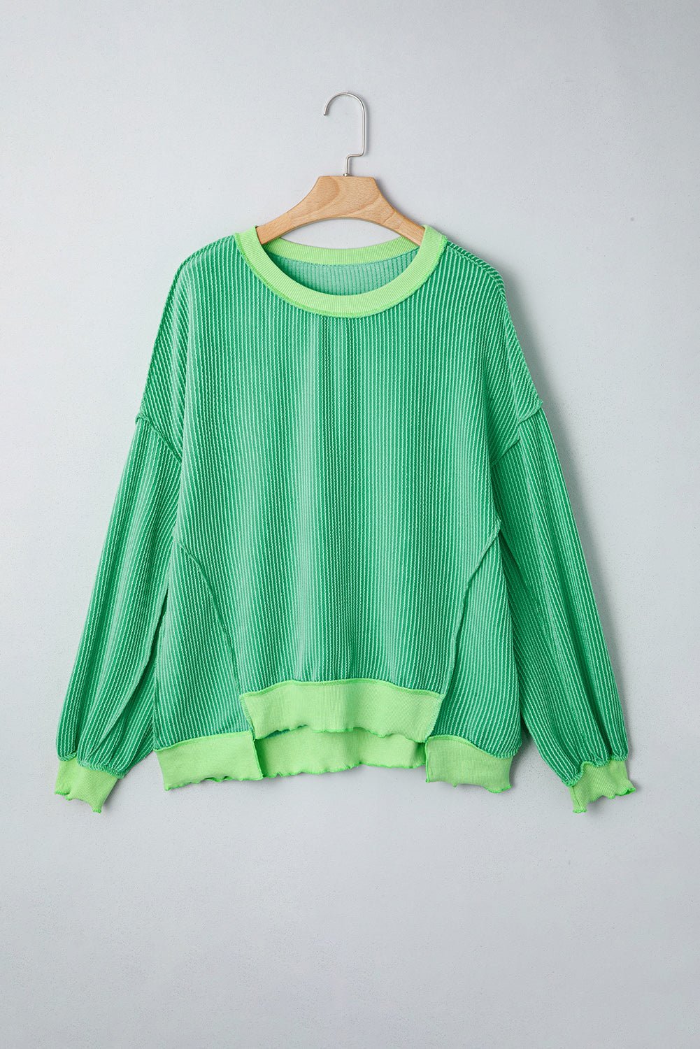 Green sweater on a wooden hanger against a light gray background
