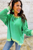 Woman wearing a green sweater with a textured pattern, smiling outdoors.