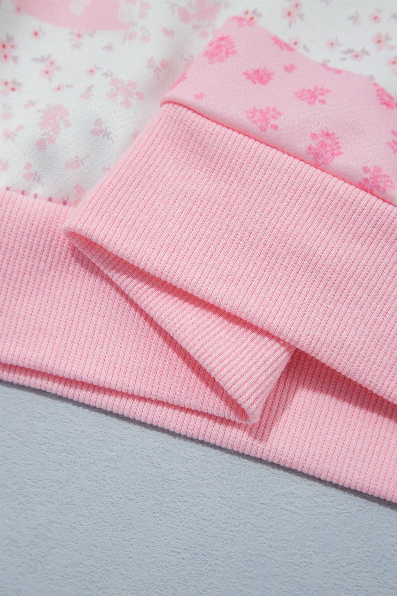 Folded pink ribbed knit garment with matching floral fabric underneath.