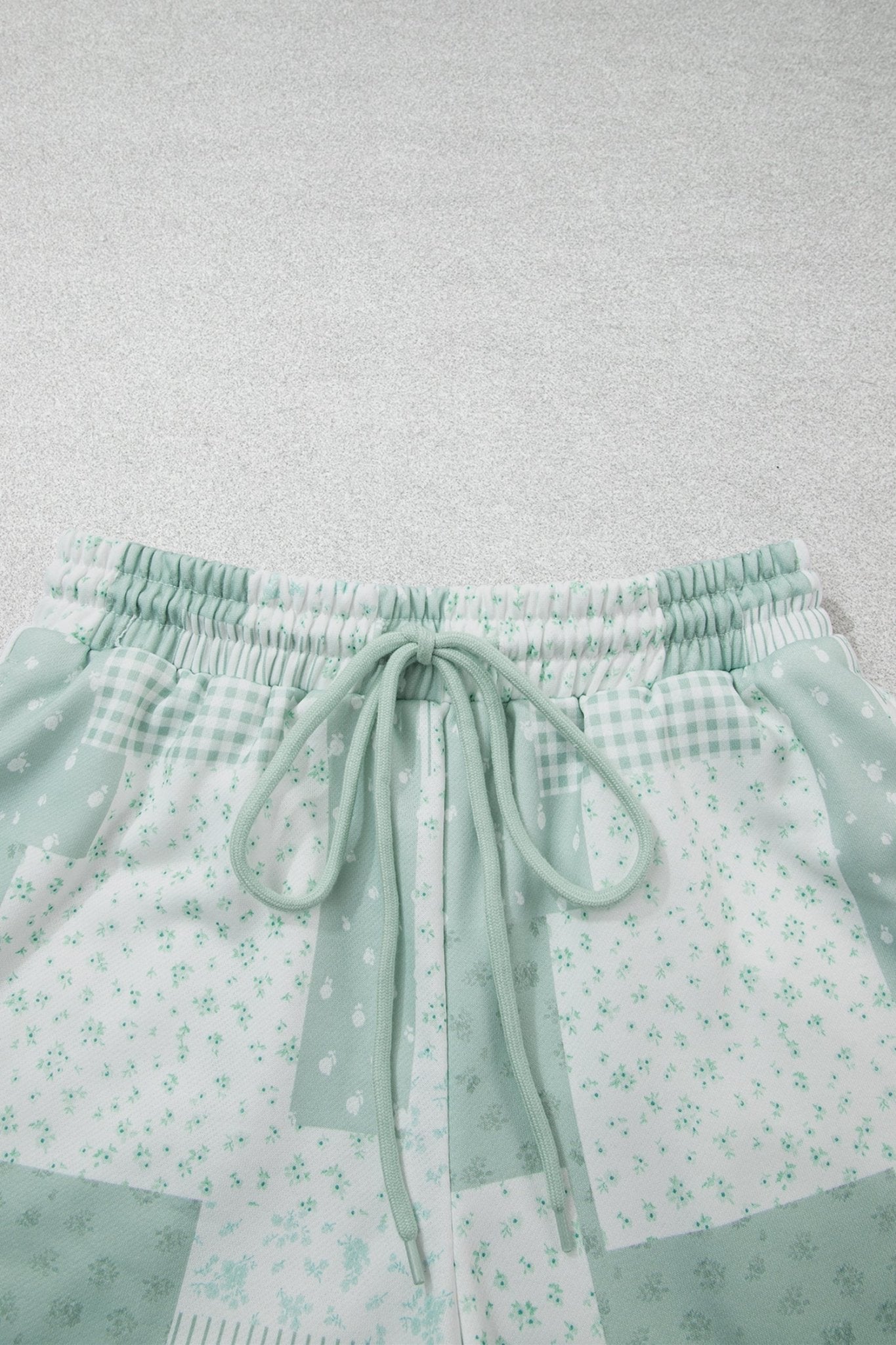 Mint green patchwork shorts with gingham, floral print, and drawstring.