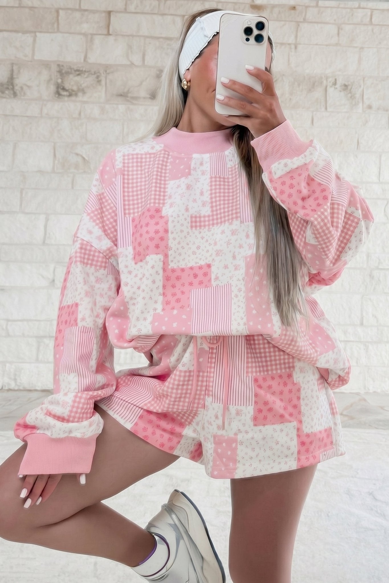 Woman taking a mirror selfie in a soft pink and white floral patchwork sweatshirt and shorts set.