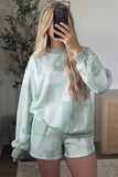Matching sage green floral and pattern patchwork lounge top and shorts set in mirror selfie pose.