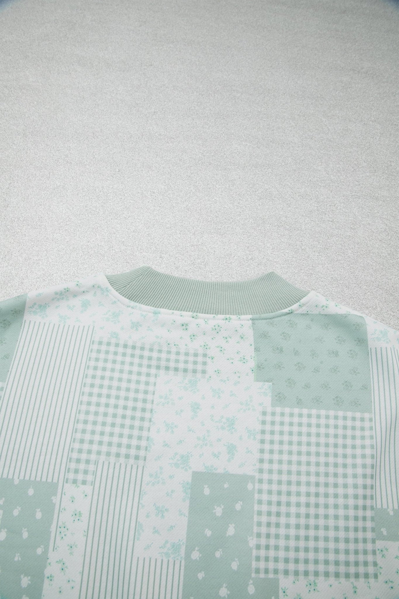 Light green and white patchwork sweatshirt with stripes, gingham, and floral prints.