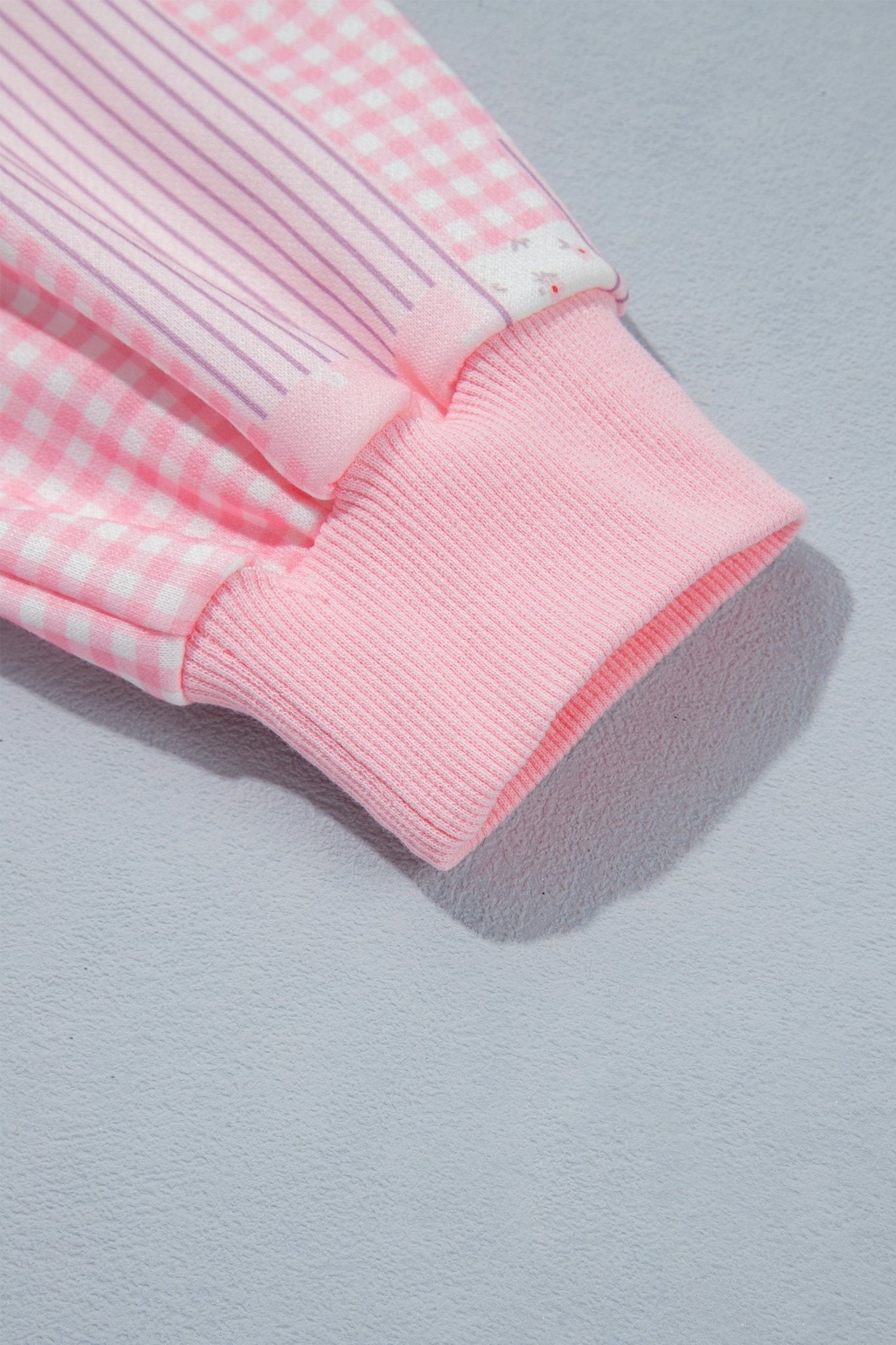 Pink ribbed cuff with gingham and striped fabric panels.