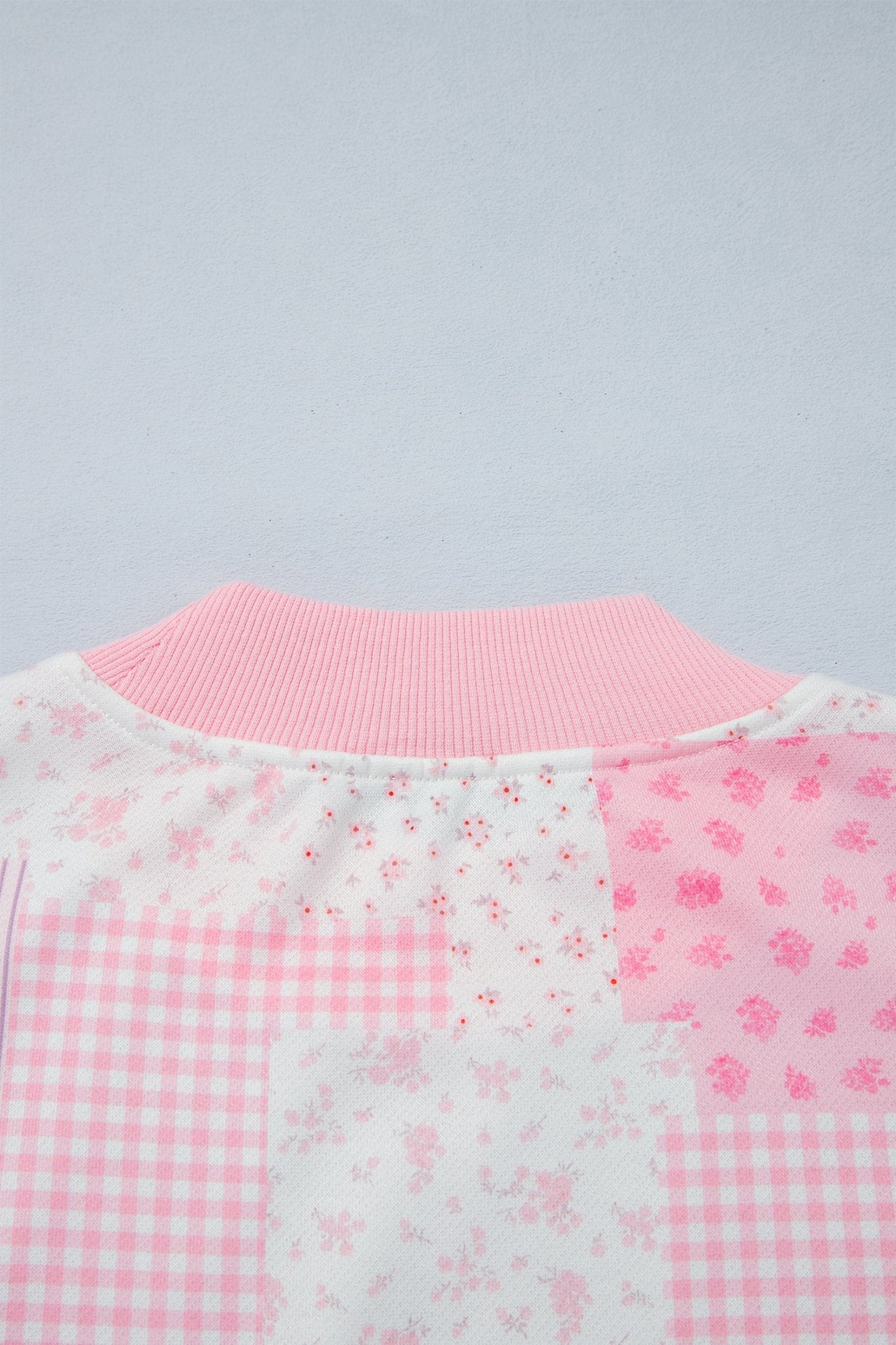 Pink and white patchwork garment with ribbed collar, gingham, and floral panels.