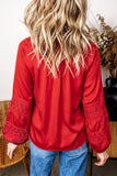 Back view of woman in bright red blouse with lace cuffs and blue jeans.
