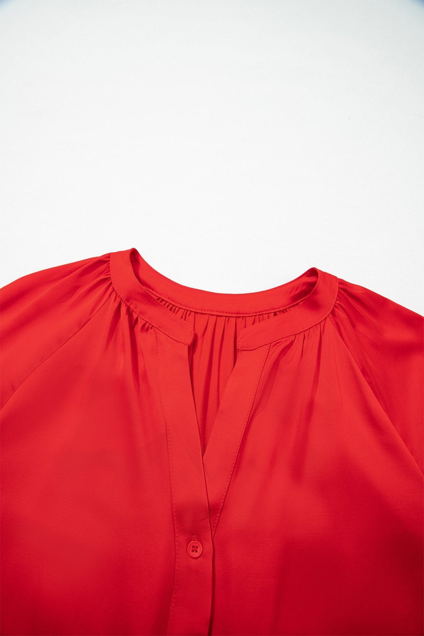 Close-up of bright red blouse with gathered neckline and partial button placket