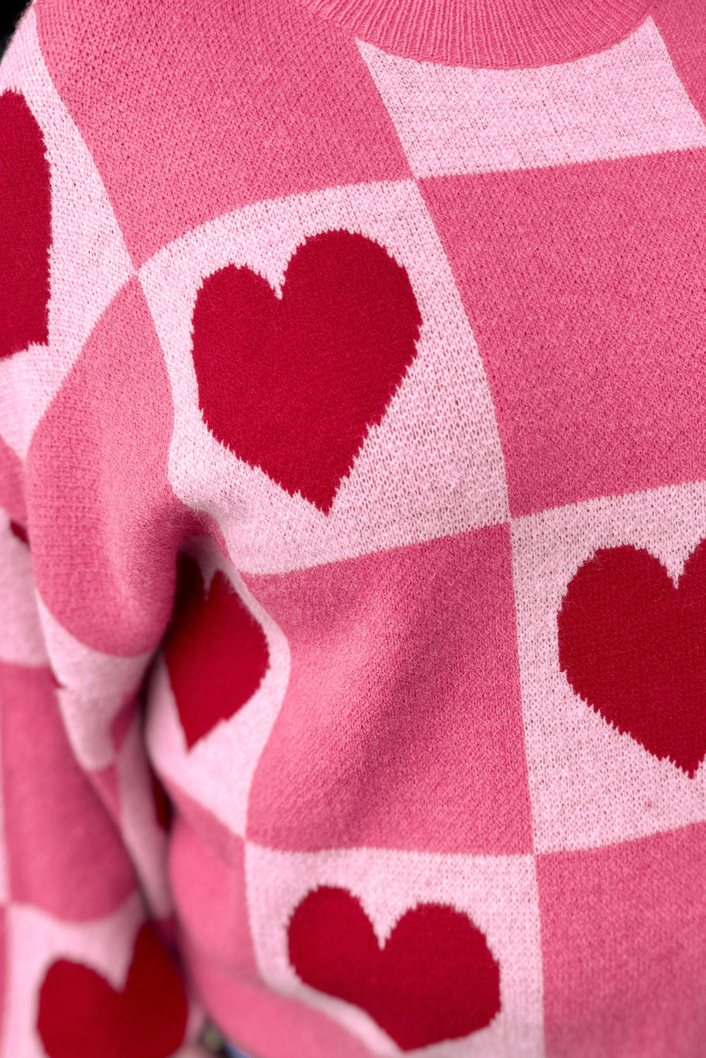Close-up of red heart and pink checkerboard knit on Valentine sweater