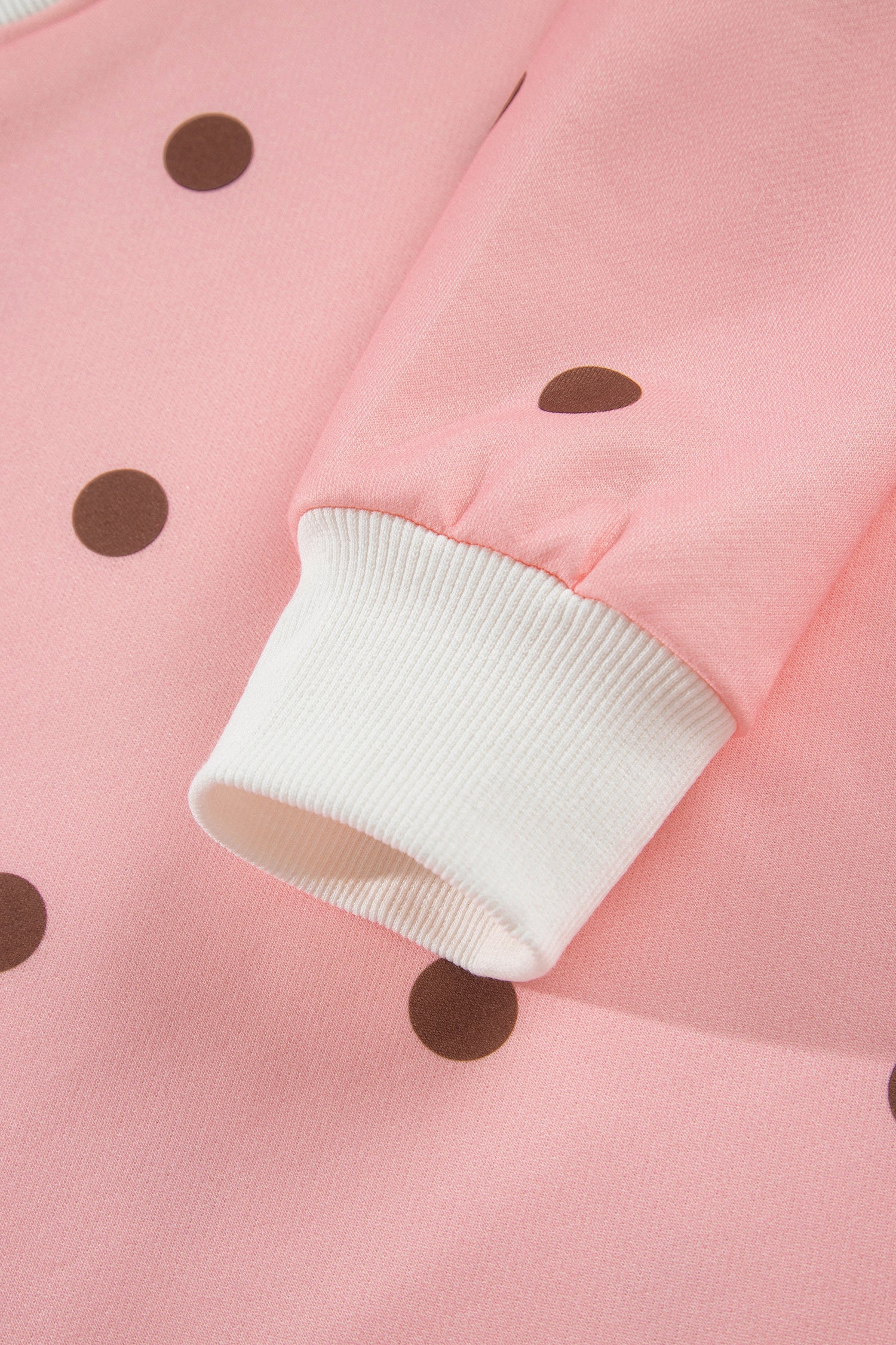 White ribbed sleeve cuff on pink polka dot top, close-up