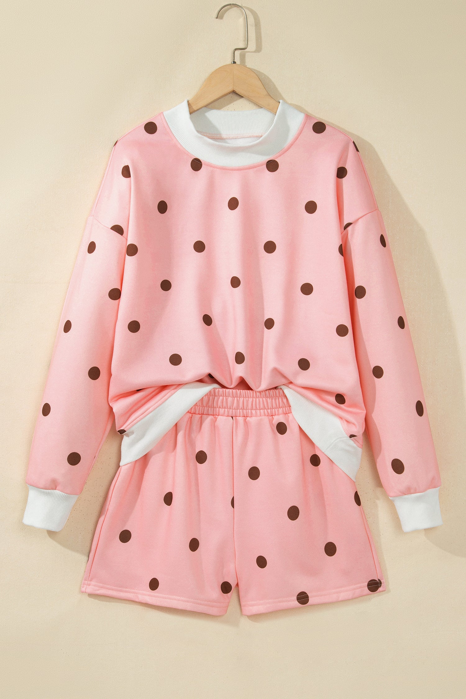 Pink polka dot top and shorts set on hanger, front view