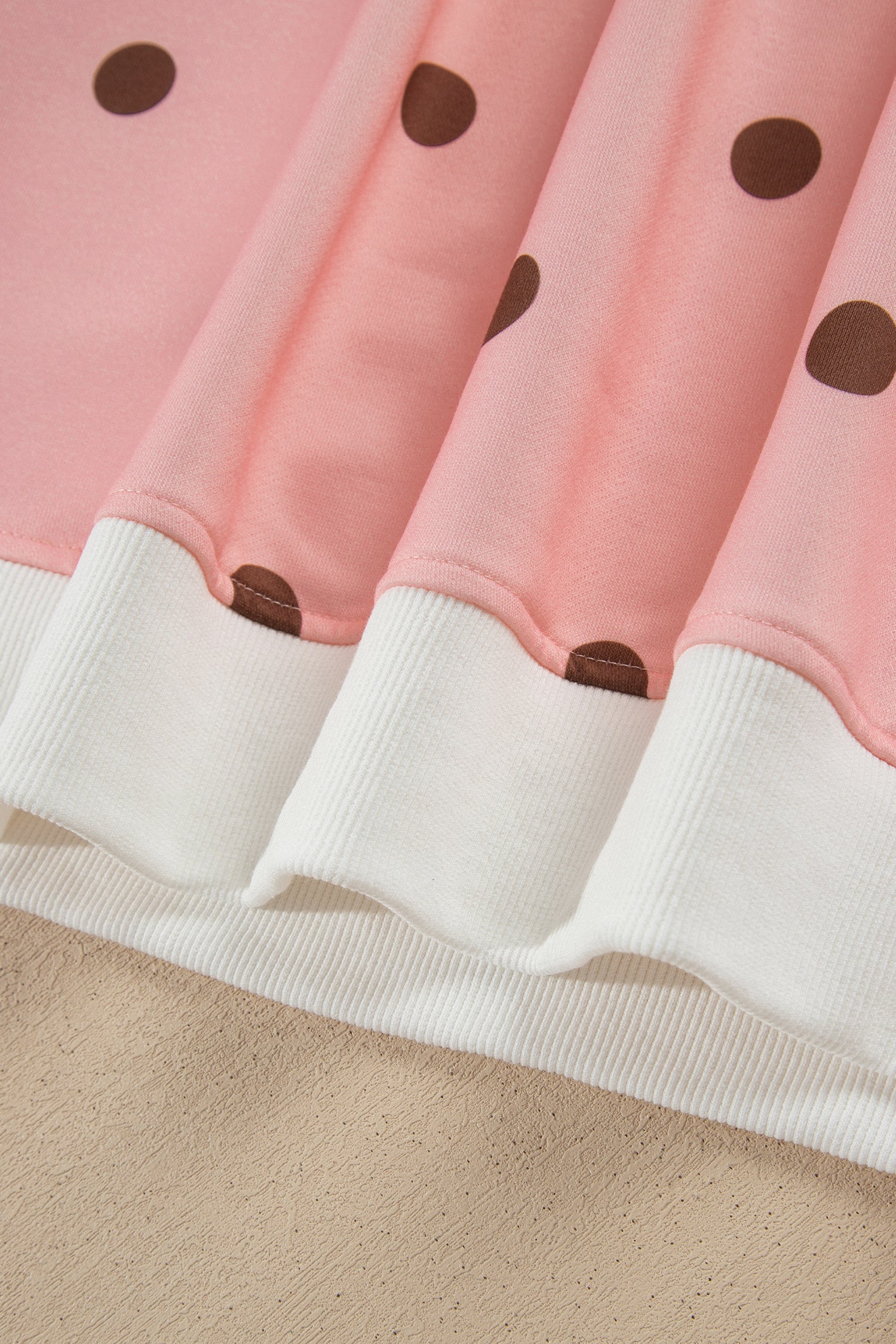 White ribbed hem band on pink polka dot top, close-up