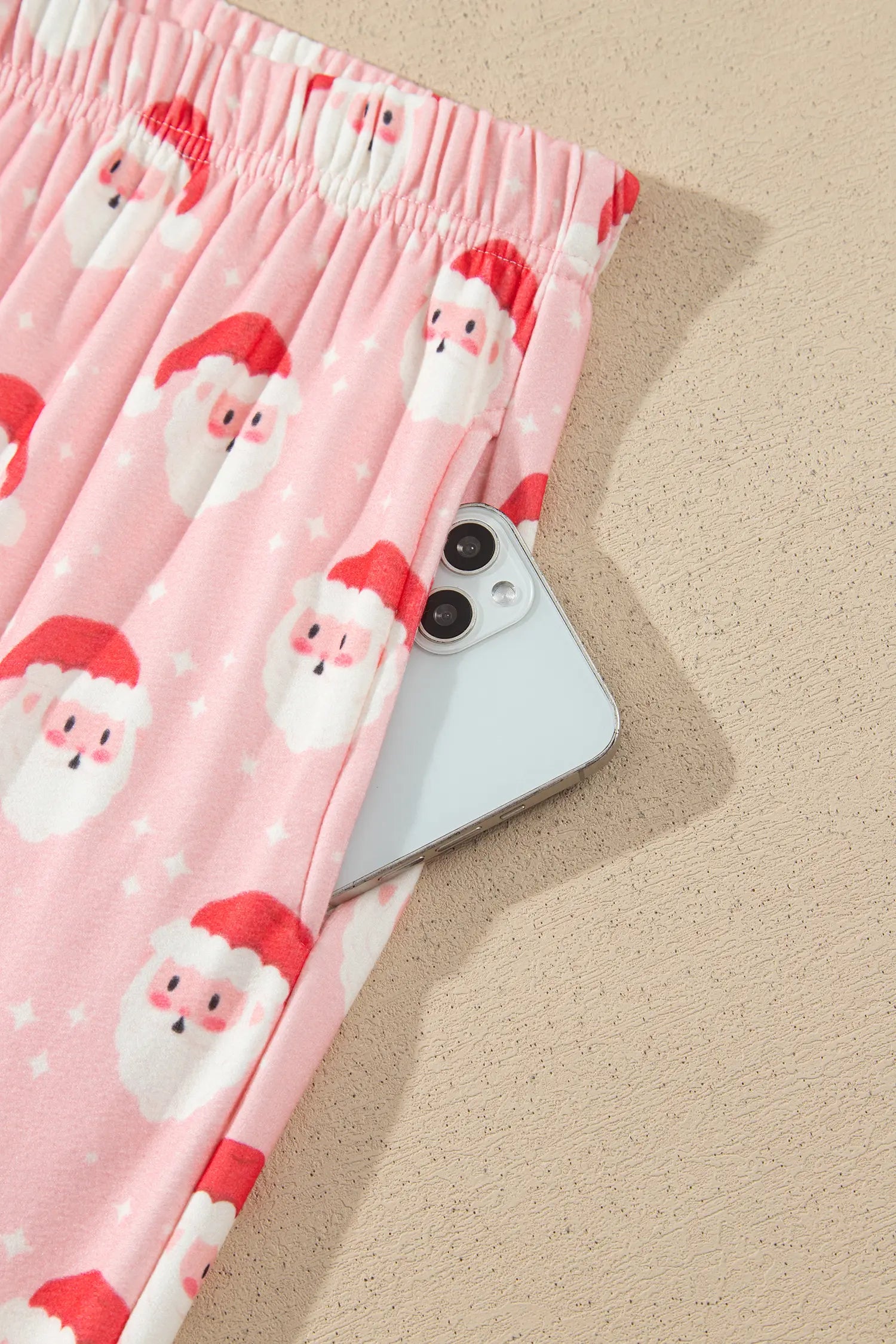 Elastic waist and side pocket holding a phone on pink Santa print lounge pants