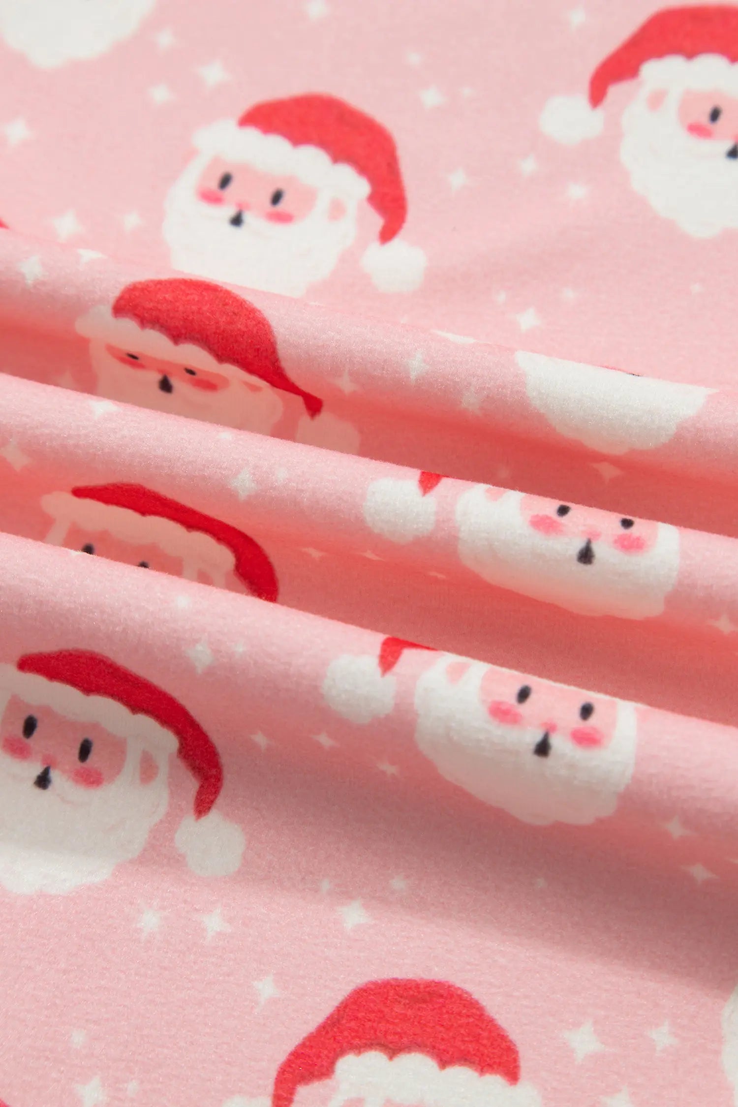 Close-up of Santa face and white star print on soft pink fabric