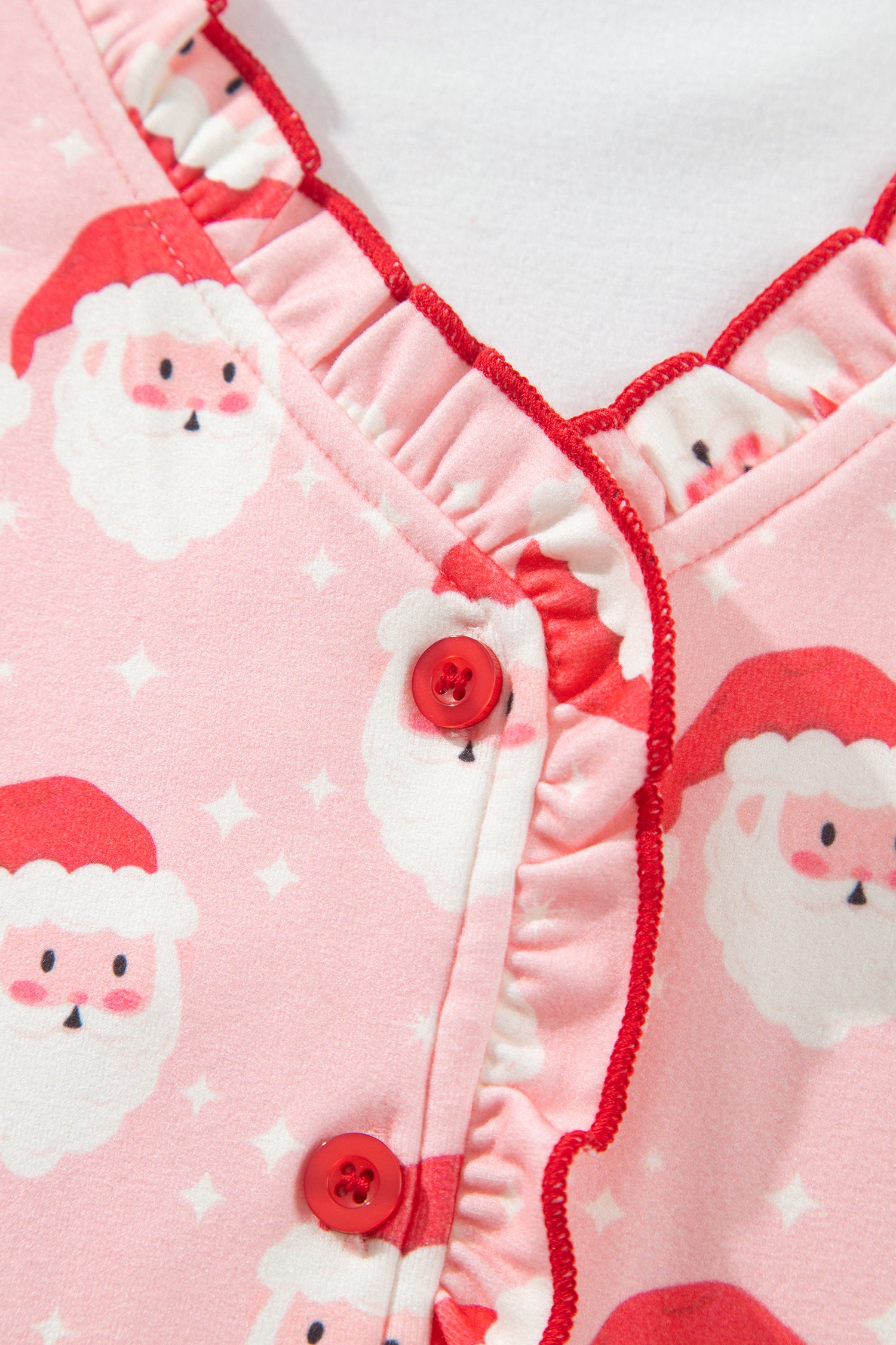 Red ruffle trim and red buttons on pink Santa print pajama top placket