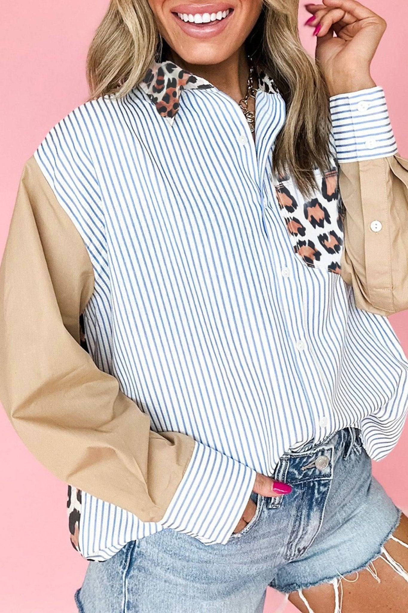 Woman wearing a striped shirt with beige sleeves and leopard print accents on a pink background