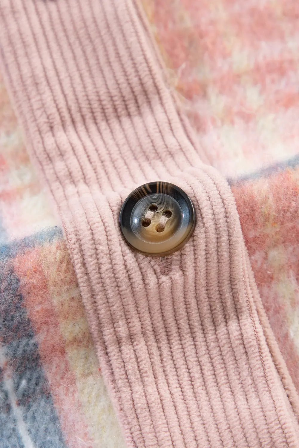 Close-up of a pink textured fabric with a button on a floral background