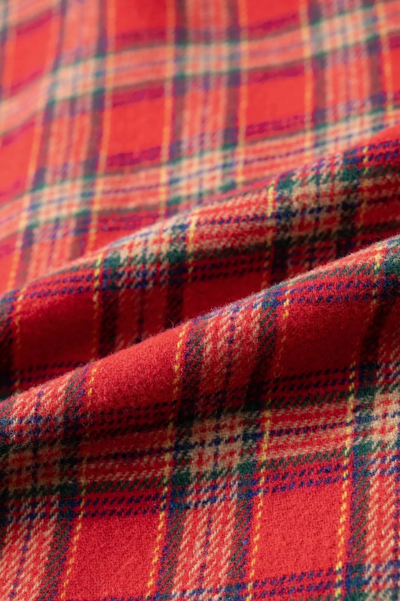 Close-up of red plaid fabric with green, blue, and yellow stripes.