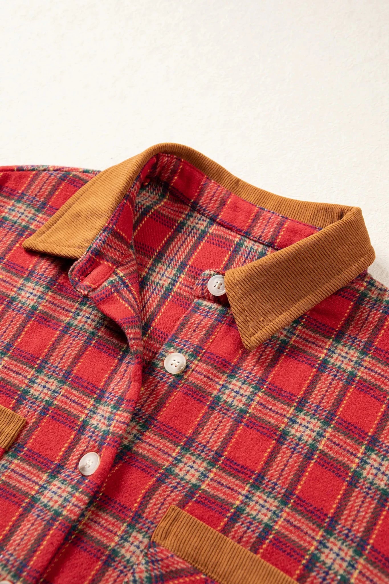 Close-up of red plaid shirt with tan corduroy collar and chest pocket.
