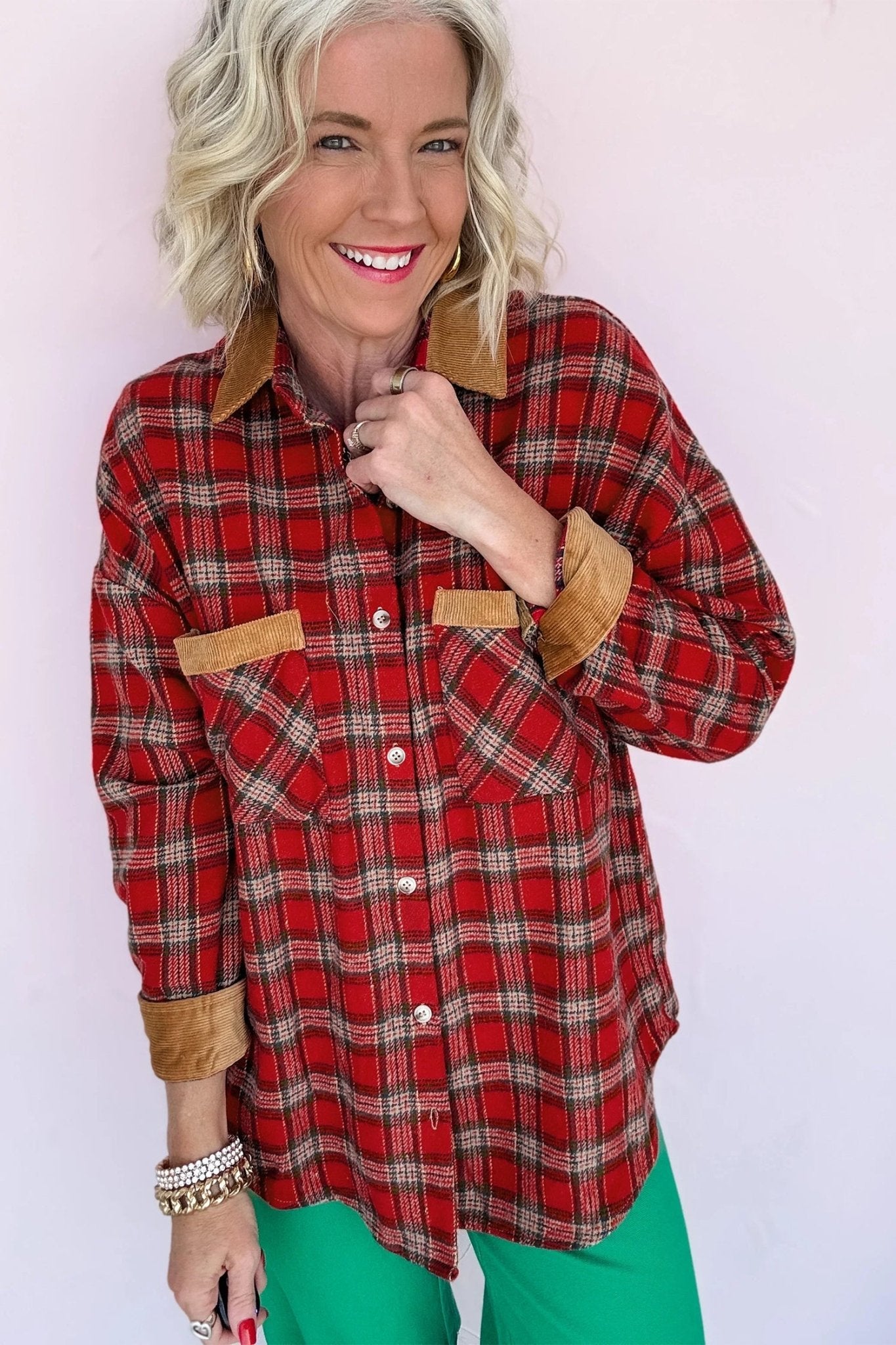 Smiling woman in red-brown plaid shirt with tan trim and bright green pants.
