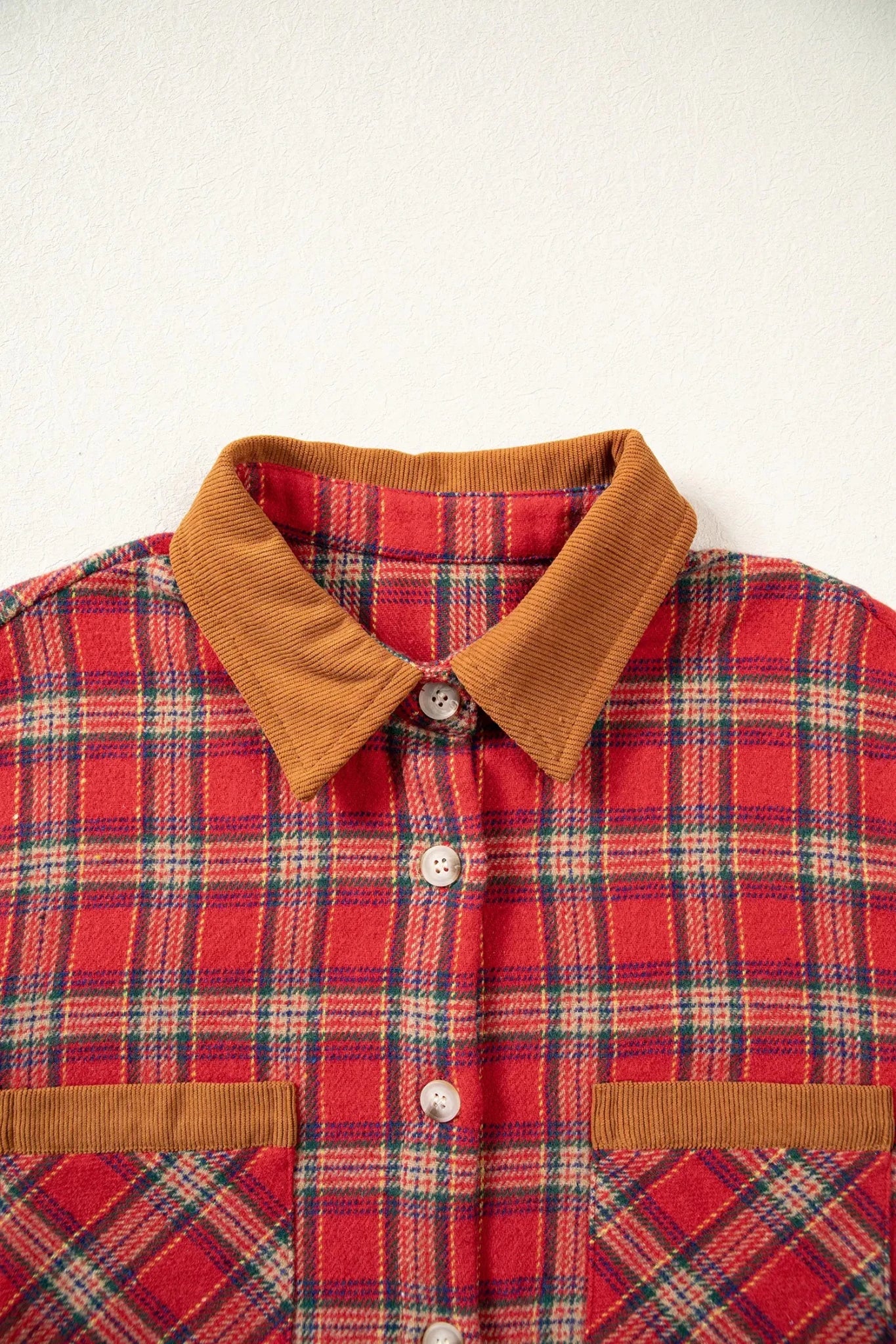 Close-up of red-navy plaid shirt with brown corduroy collar and pocket flaps.
