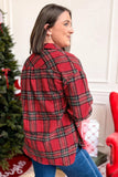 A woman wearing a red and black plaid flannel shirt, shown from the back in a holiday-themed indoor setting with a Christmas tree and red chair in the background.