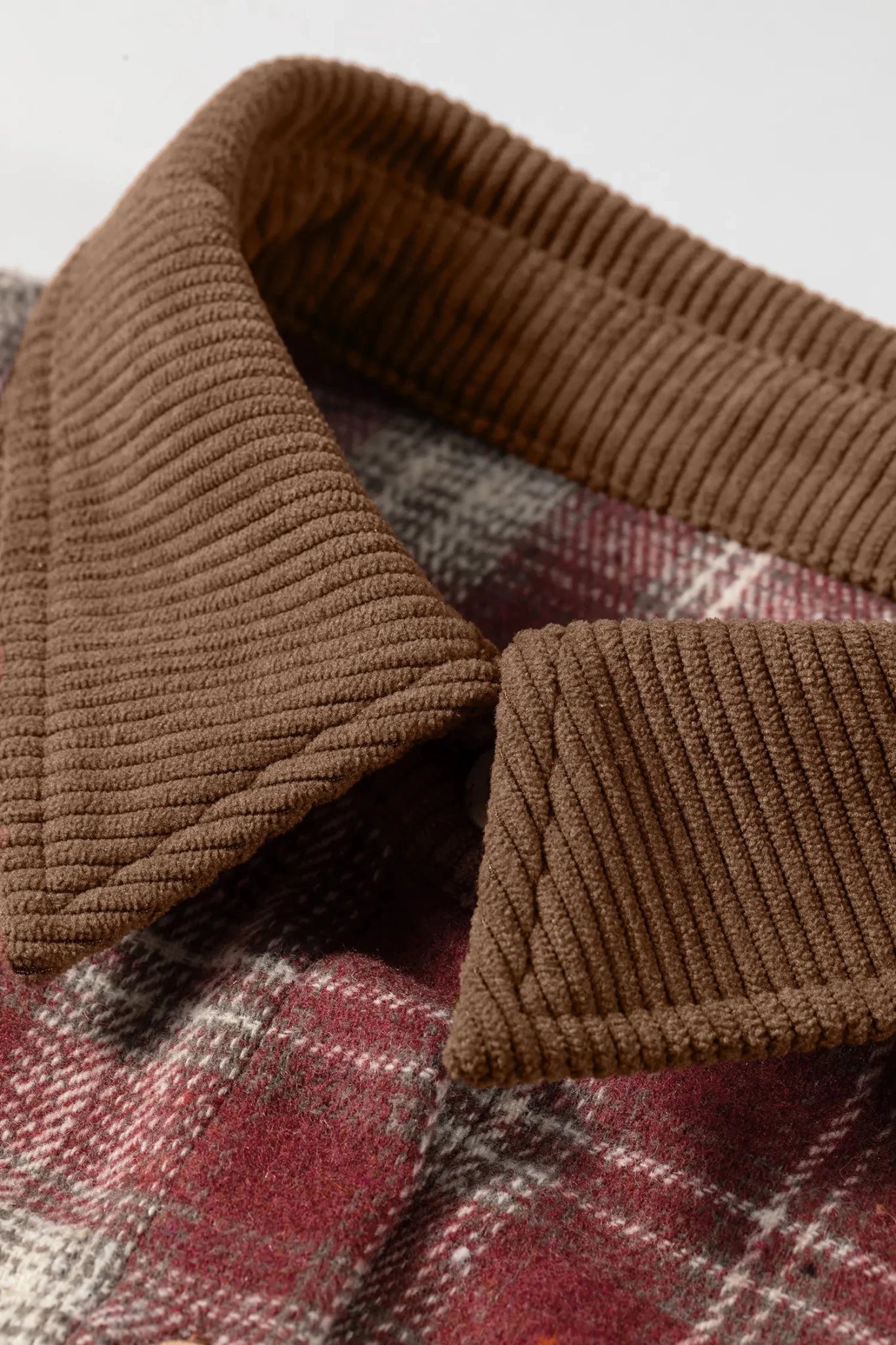 Close-up of a brown ribbed collar on a plaid fabric background