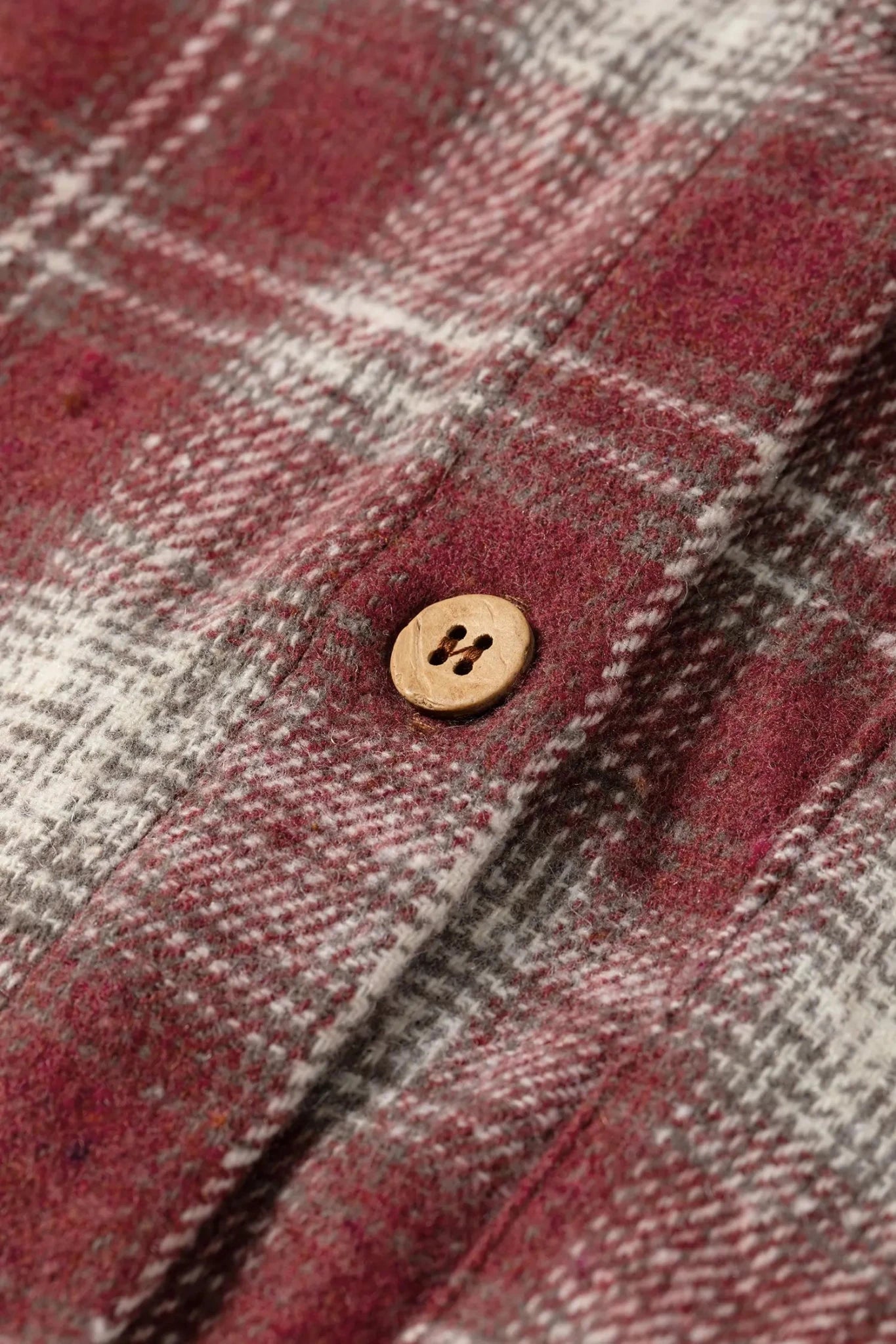 Close-up of a plaid fabric with a button, featuring red and gray colors.