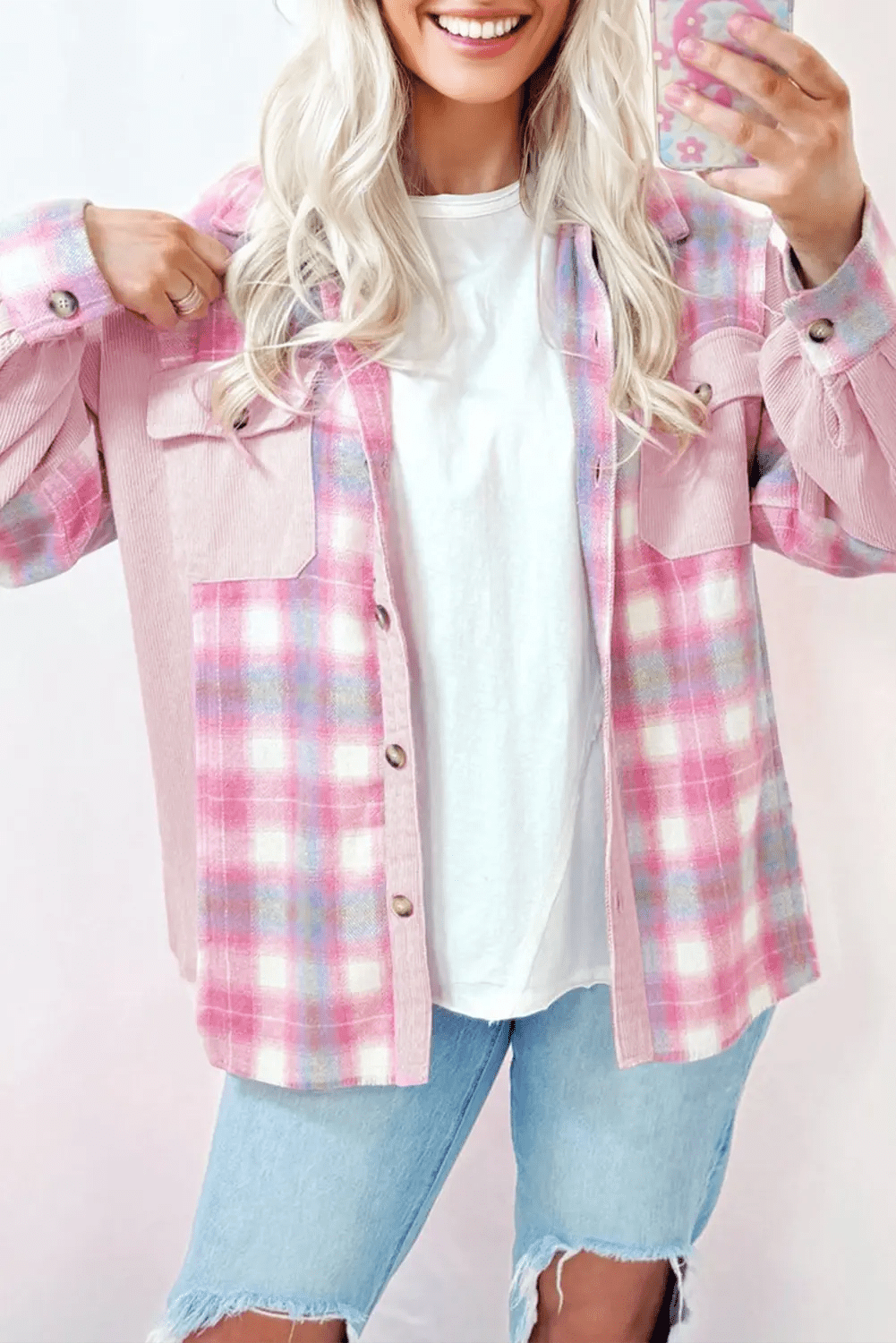 Person wearing a pink plaid shirt over a white top with light blue jeans on a white background