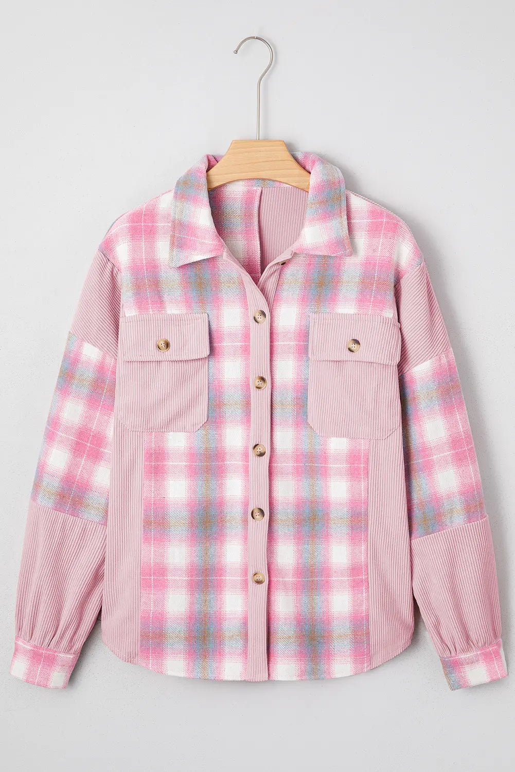 Pink plaid shirt jacket with textured corduroy sleeves and chest pockets, hanging on a wooden hanger against light gray.
