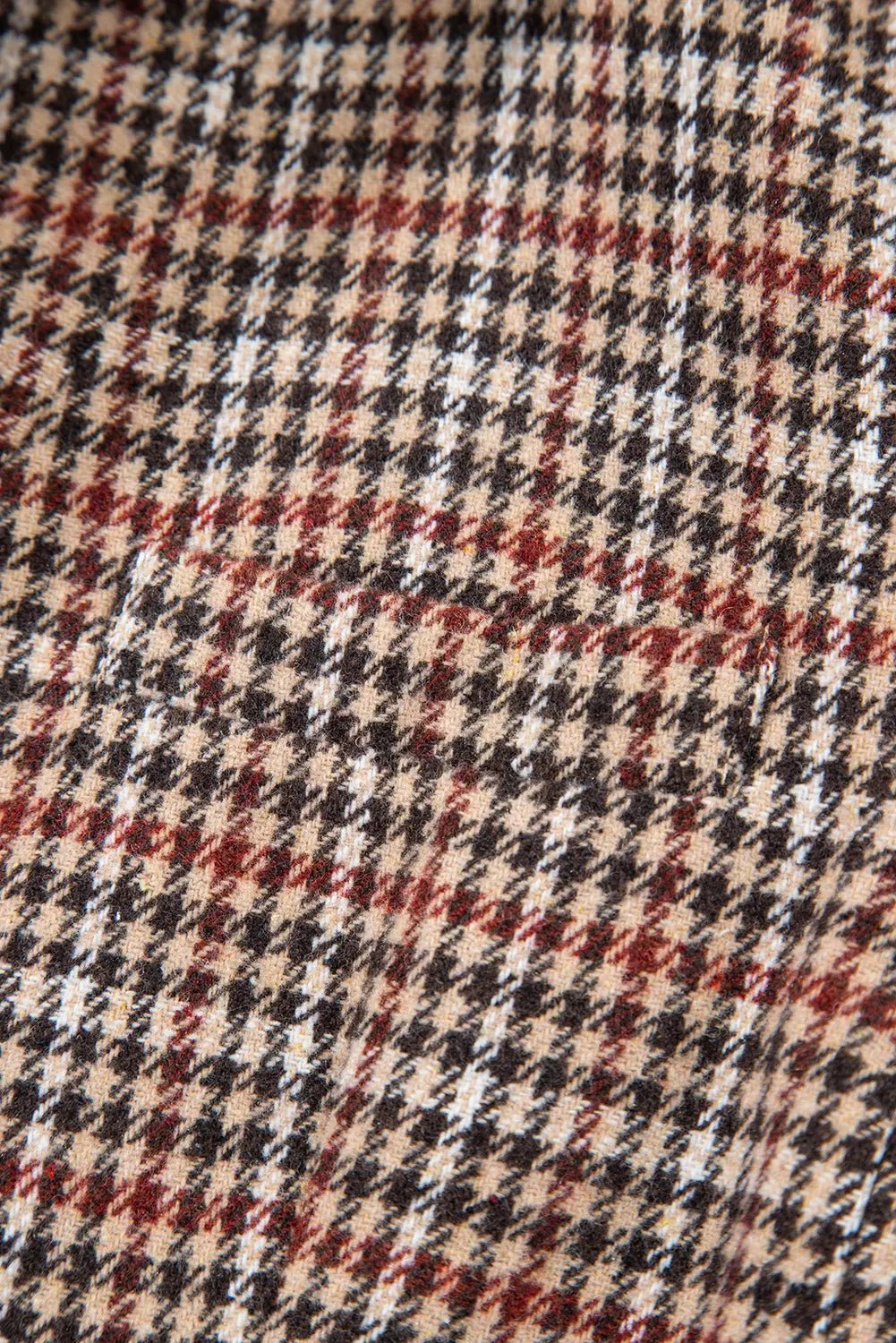 Close-up of a houndstooth pattern fabric with black, red, and beige colors.