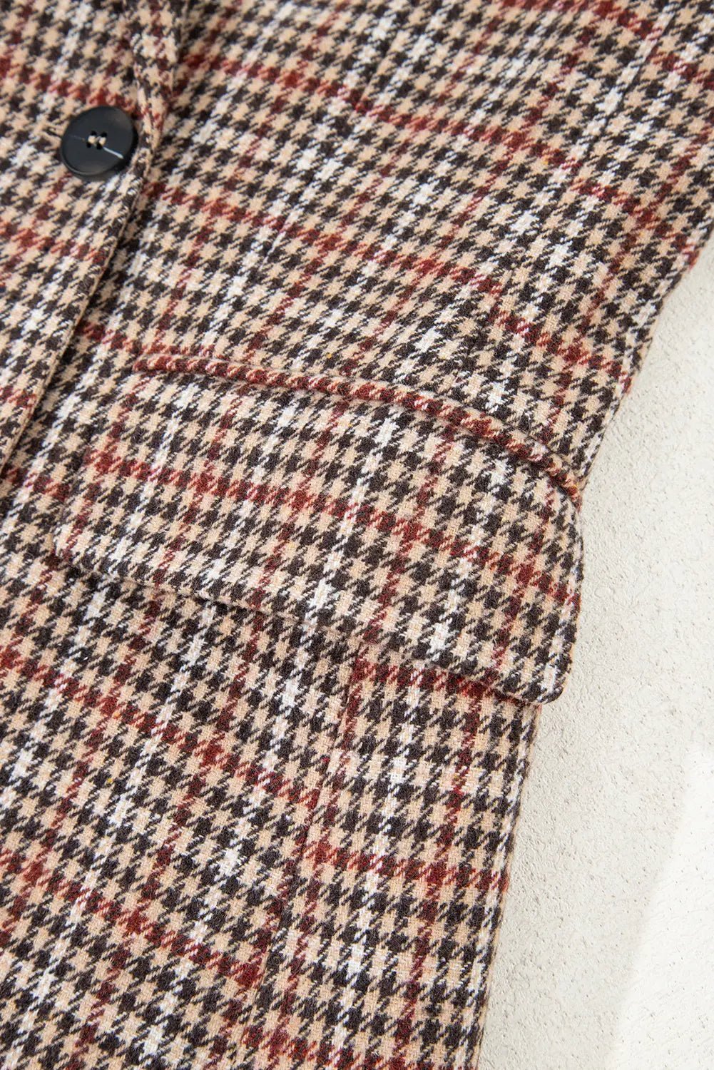 Close-up of a plaid patterned fabric with a button and white lining.