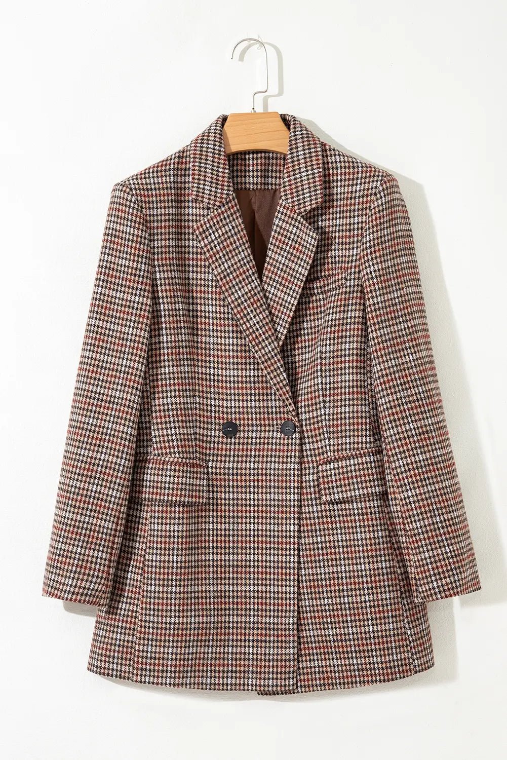 Plaid blazer on a hanger against a white background
